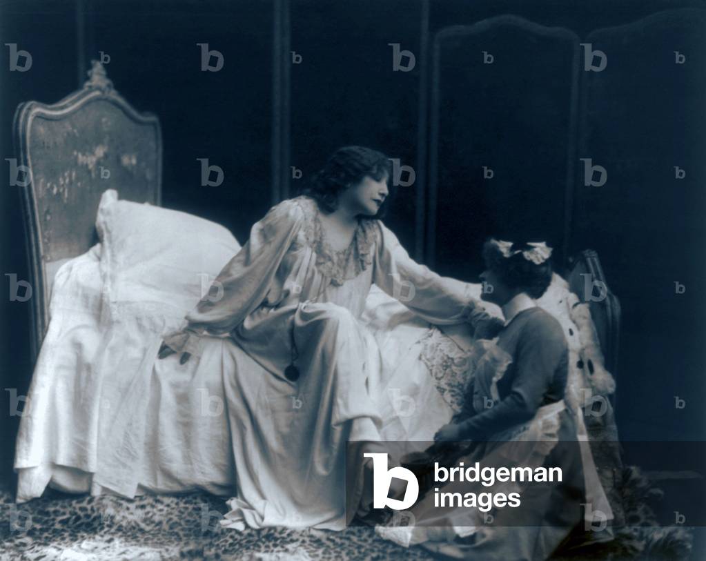 Sarah Bernhardt (1844-1923), French actress, in the role of the dying Camille, with her maid helping her put on her slippers. c. 1887