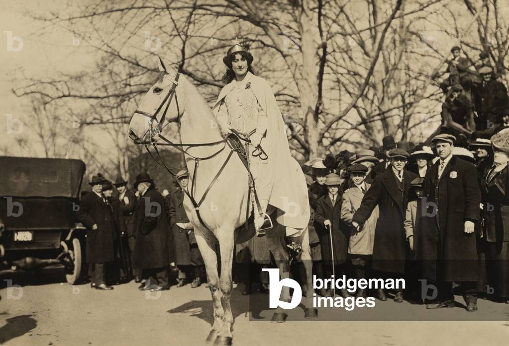 Inez Milholland, wearing white robes and a crown riding a white horse as the 'Herald' in the Women's Suffrage parade of March 3, 1913, the day prior to Woodrow Wilson's inauguration. It was the last major suffrage demonstration to use such theatrical costumes