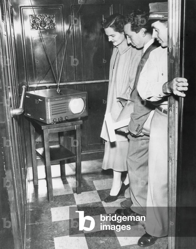 Portable television in a New York City elevator, Oct. 5, 1949. The operator brought his TV to work so he could watch the first game of the World Series between the Brooklyn Dodgers and the New York Yankees.