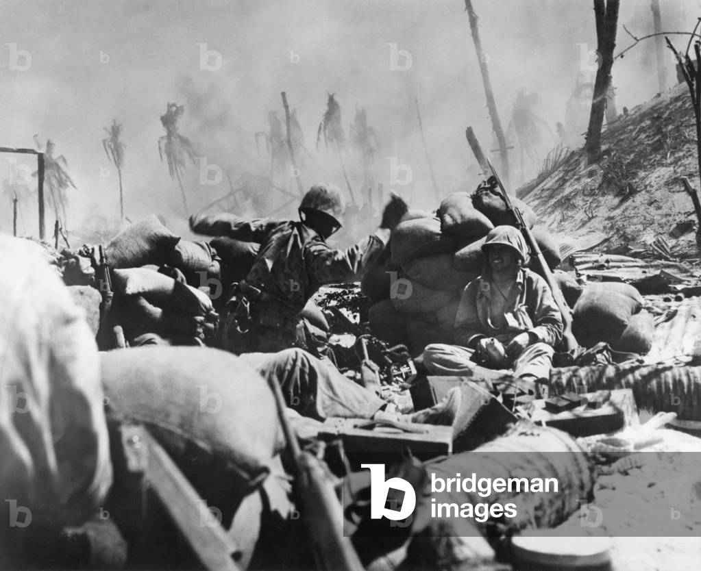 Marine about to throw a hand grenade at a Japanese pillbox on Tarawa, Nov. 23, 1944. Smoke of the battle rolls over a hastily thrown up sandbag entrenchment from which he and other Marines fought. World War 2