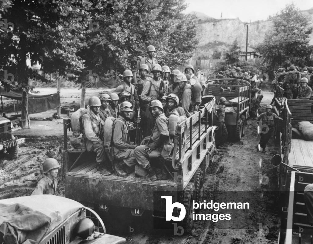 U.S. Soldiers move up to the firing line in Korea on July 18, 1950. Troops on occupation duty in Japan were the first fight the North Korean invaders. African Americans in the near truck are with the now integrated 24th Infantry Regiment. Korean War, 1950-53