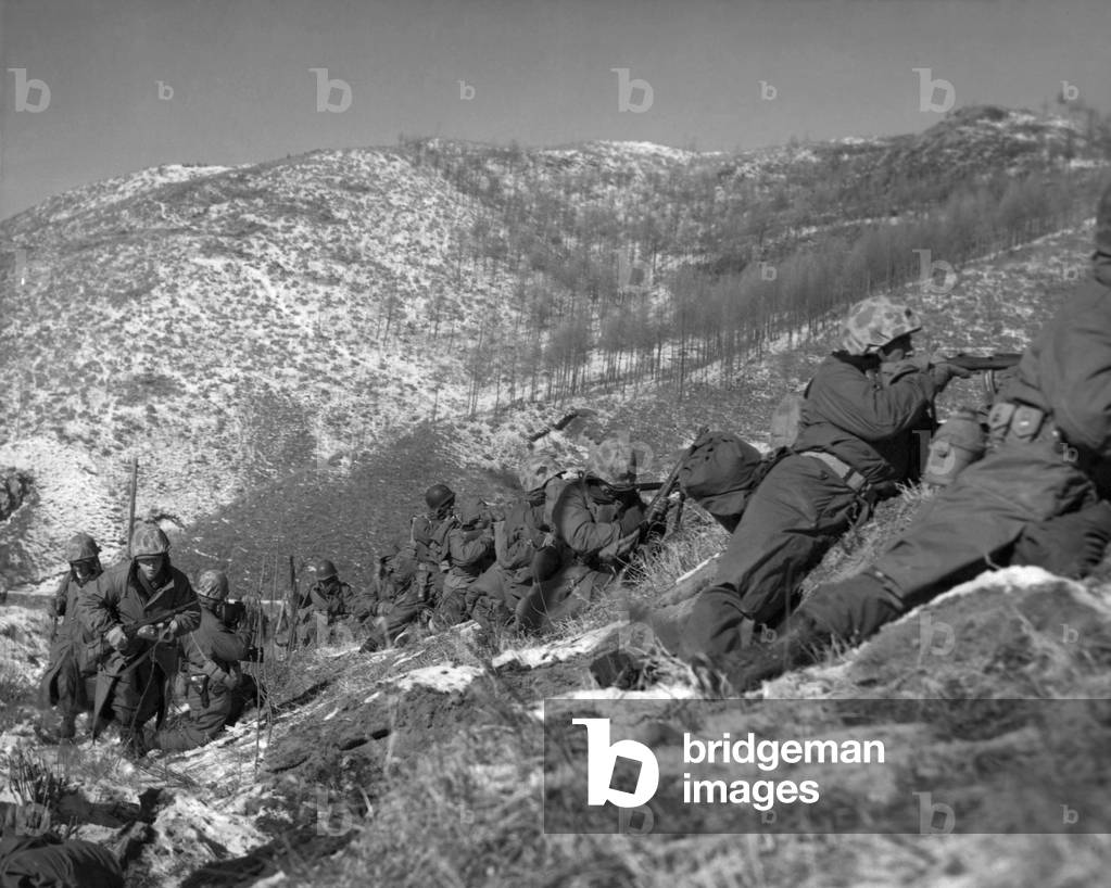 U.S. Marine infantrymen engage Chinese forces at the Chosin Reservoir. They take cover behind large boulders. Dec. 5, 1950. Korean War, 1950-53