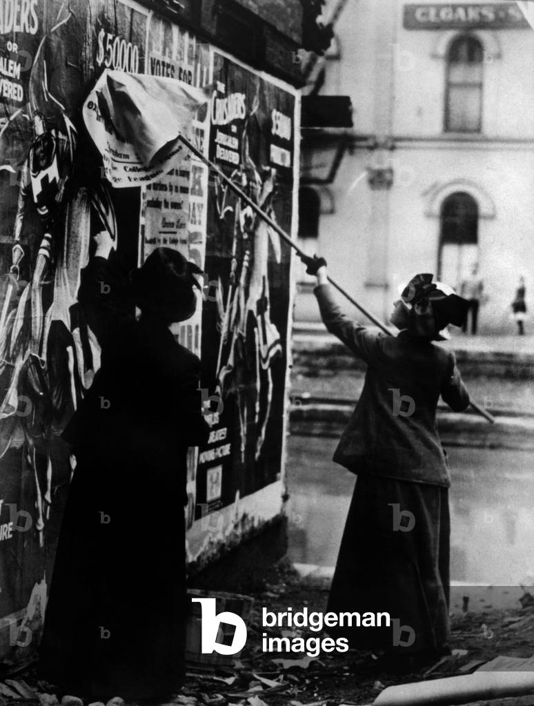 Femme colleuse d'affiche: Two suffragettes posting a billboard in New York City, c. 1917.