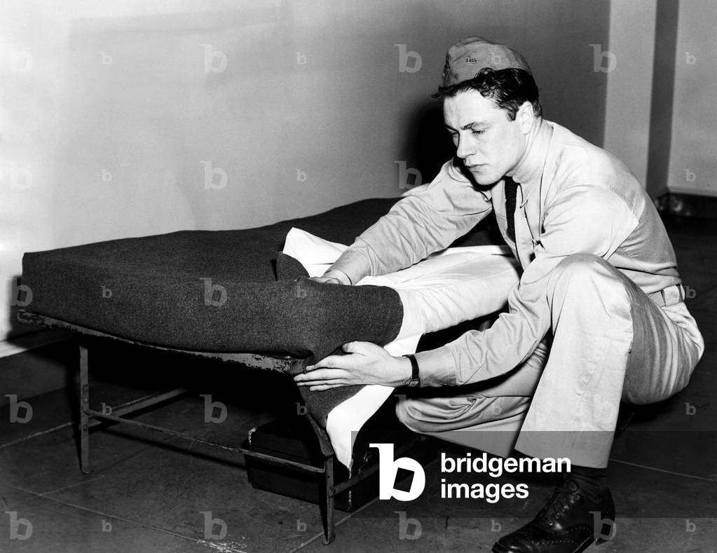 An army recruit learning how to make his bed in order to pass inspection, April, 1941.