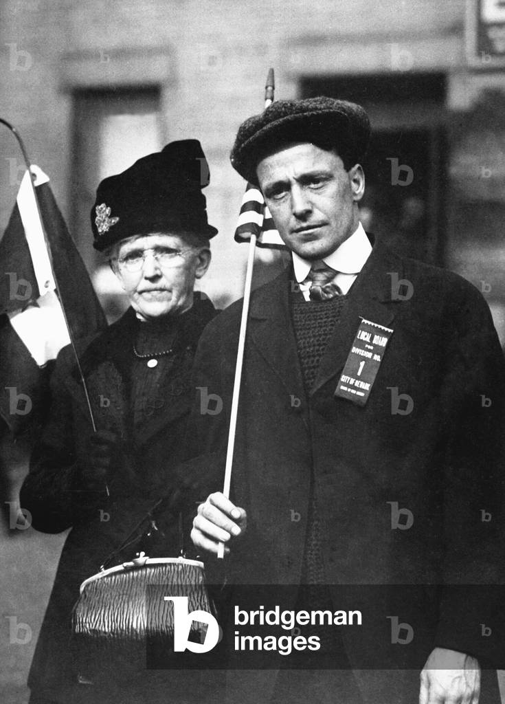 Mother escorting her son to train, who is bound for training camp. He carries a flag and wears a ribbon reading, 'Local Board for Division No. 1, City of Newark. World War I. c. 1918
