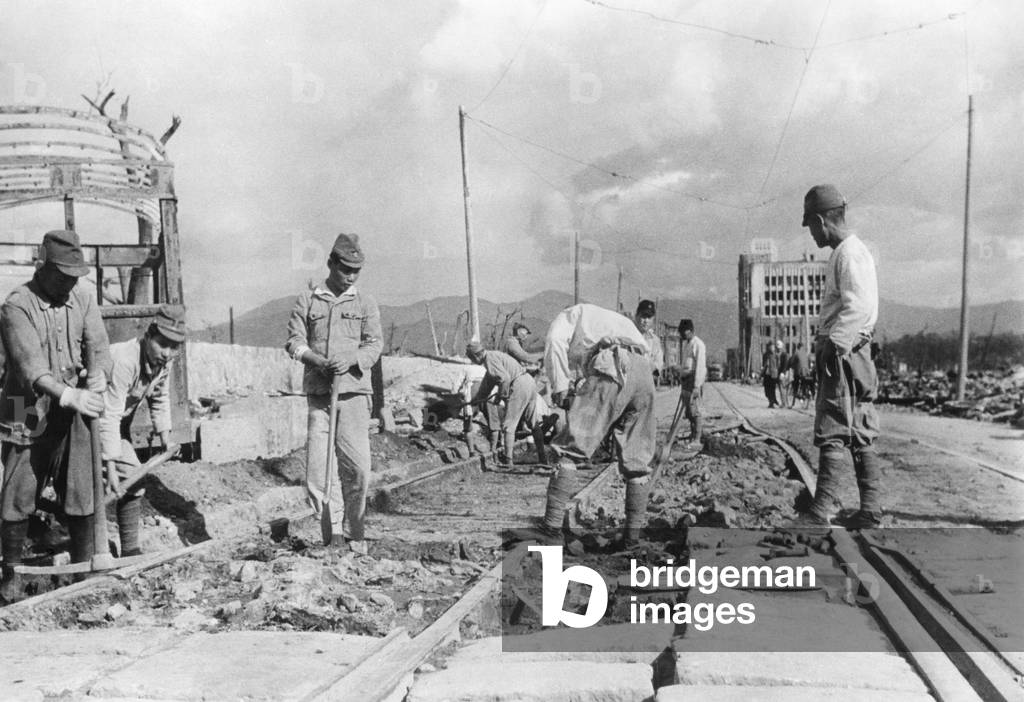 Japanese soldiers repair street car tracks in devastated Hiroshima after the end of World War 2. It is possible these men are civilians, wearing the only clothing they have, their military uniforms. Sept-Nov. 1945