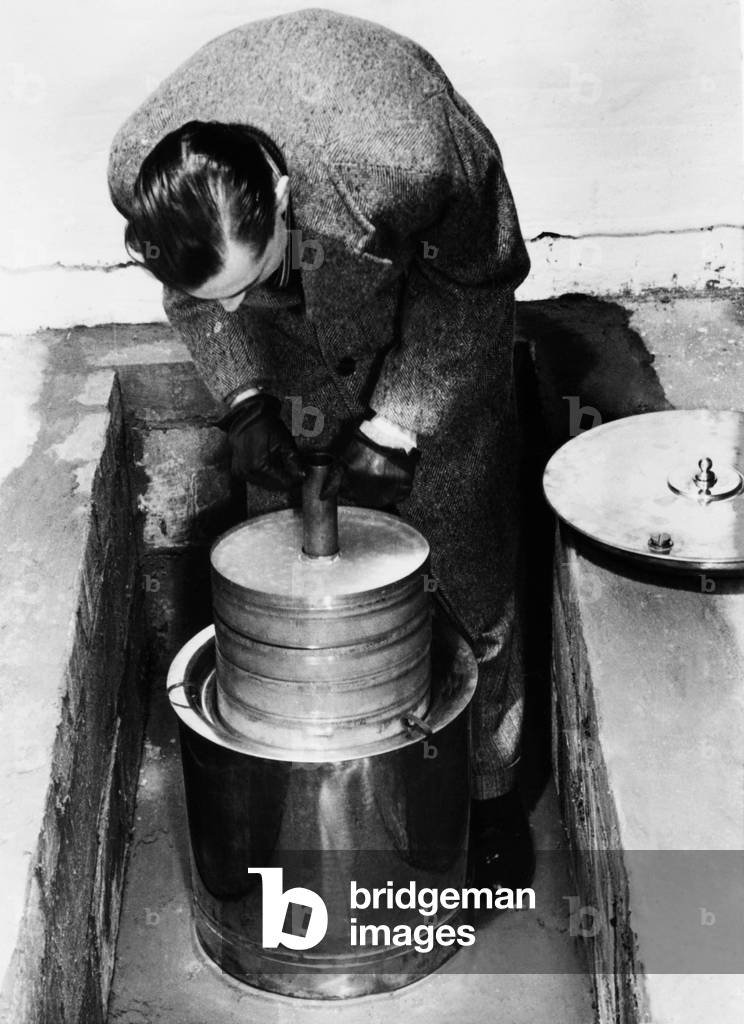 British scientist Robert Barker, 26, claims to have built an portable atomic pile. He said the ashcan-sized apparatus could produce quality radioactive isotopes. Its dangerous radiation was reduced by the copper container and placement in a concrete block well.