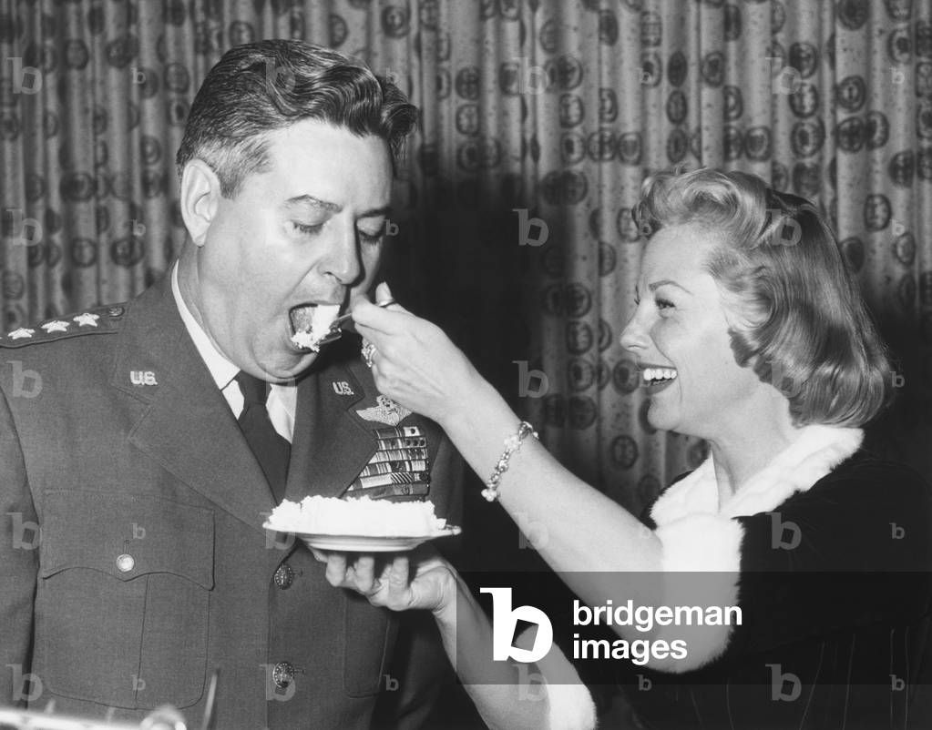 June Allyson serving cake to General Curtis LeMay on the 9th anniversary of SAC. A preview of Allyson's new film, STRATEGIC AIR COMMAND was shown at the party held in Omaha Global Headquarters for SAC, March 31, 1955