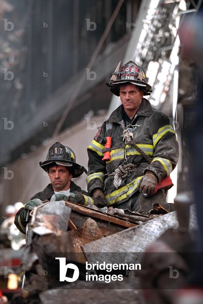 NYC Firemen, grim and geared for rescue/recovery work at the destroyed World Trade Center, NYC. They have a high seat to view President George W. Bush's visit to Ground Zero on Sept. 14, 2001