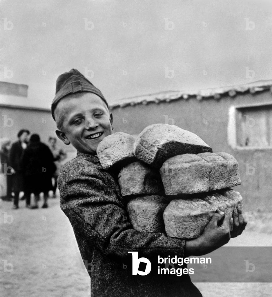 Polish youngster with bread made from flour supplied by the American Red Cross. He is exiled from Poland and possibly in the North African theater during World War 2, 1943