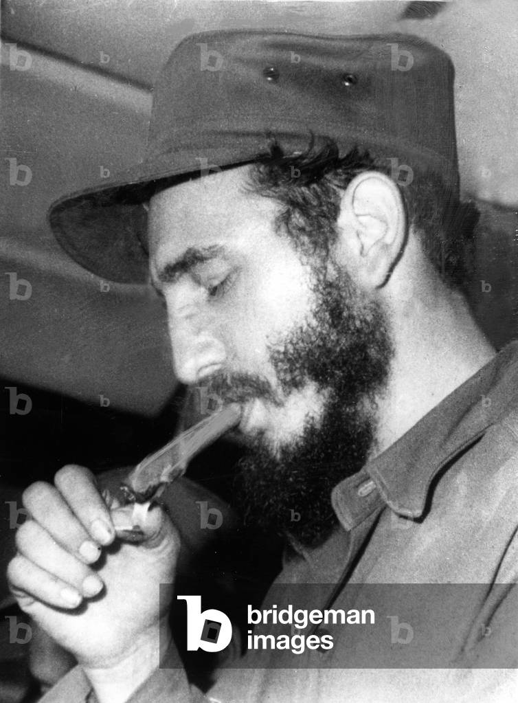 FIDEL CASTRO, lighting a cigar, 1967