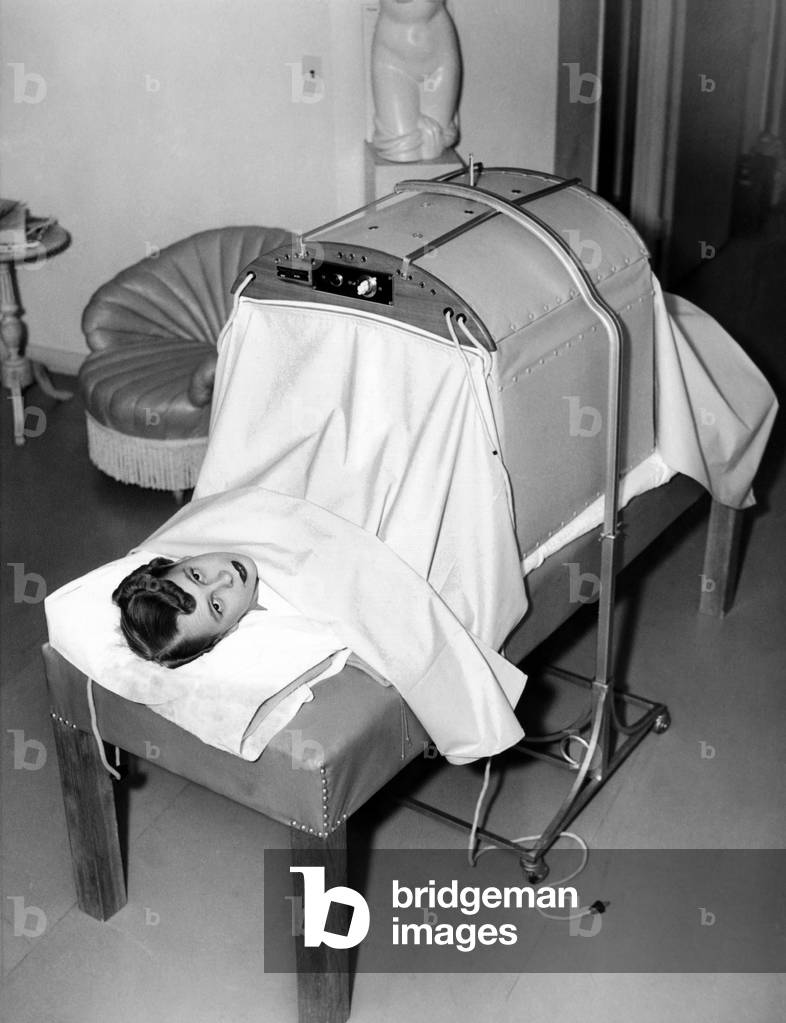 Helena Rubinstein: Helena Rubenstein Fifth Avenue Salon. Hair treatment is followed by massage. First, the baking machine where electrically heated blankets augment the infrared heat massage. This is followed by a manual massage. March 1937. (CSU_ALPHA_1425) CSU Archives/Everett Collection