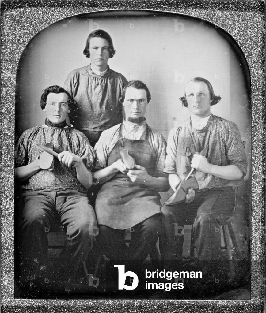 Occupational group portrait of four cobblers, holding shoes and shoe making equipment. sixth plate daguerreotype ca 1840-1860