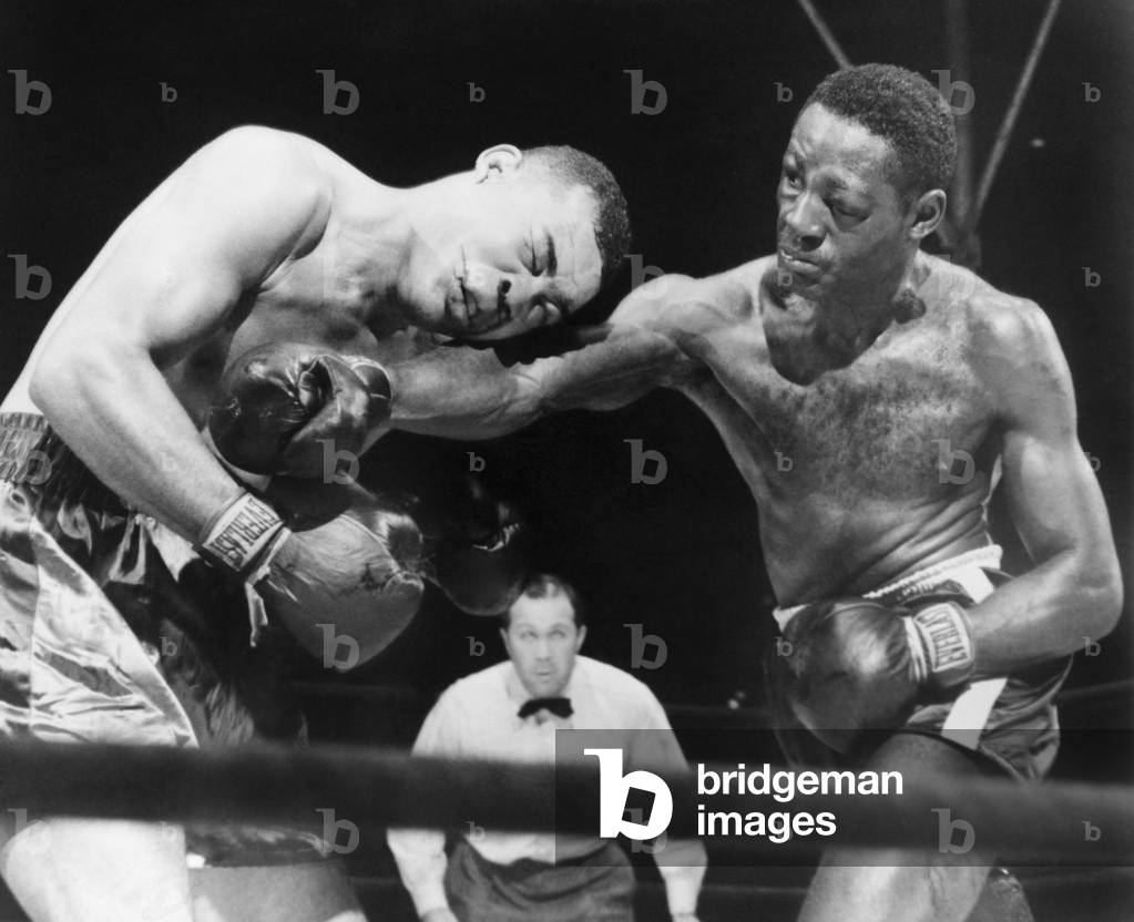 Joe Louis (left), takes a hard right punch in the midsection from Ezzard Charles, in a heavyweight title bout, at New York's Yankee Stadium. Charles won the fight on points. Sept. 27, 1950