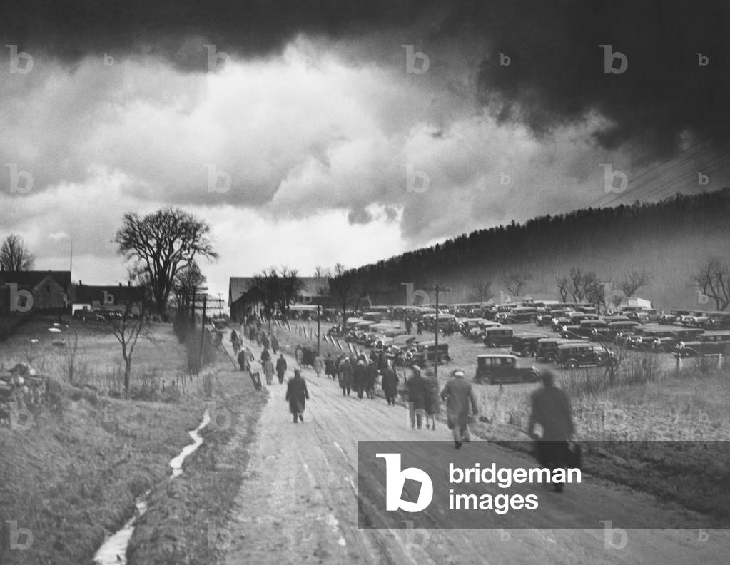 Former President Calvin Coolidge laid to rest in Plymouth, Vermont. Jan. 7, 1933. Heavy dark clouds hover over the road to Plymouth, Vermont, as citizens trudged toward the hillside grave. A local farmer provided parking space