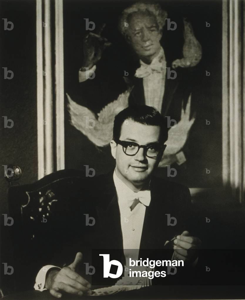 Harry Blackstone, Jr. (1934-1997) American stage magician, author, and television performer with a deck of cards. Behind him is a portrait of his famous father, The Great Blackstone