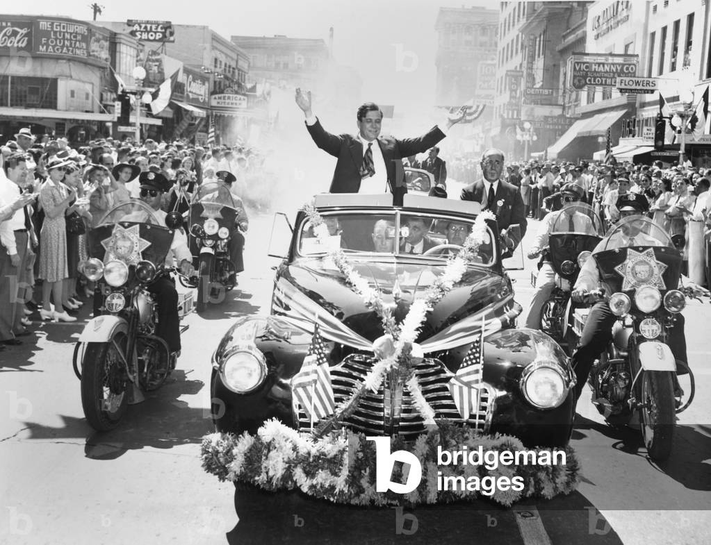 Wendell Willkie accepts the applause of the crowd in Phoenix, Arizona, on Sept. 19, 1940. His flag and flower bedecked convertible is flanked by motorcycle police