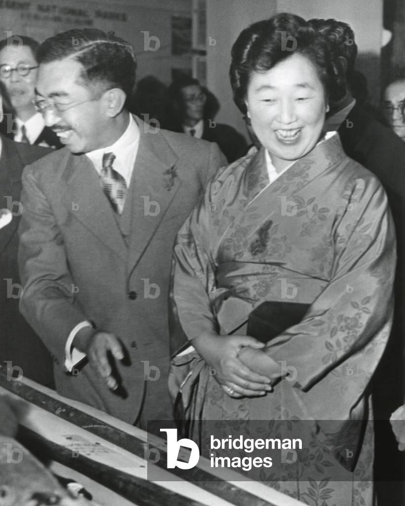 Emperor Hirohito and Empress Nagako at an exhibition at a Tokyo Department store. Oct. 27, 1949. Both wear small red feathers showing they contributed to the Japanese Community Chest Drive.