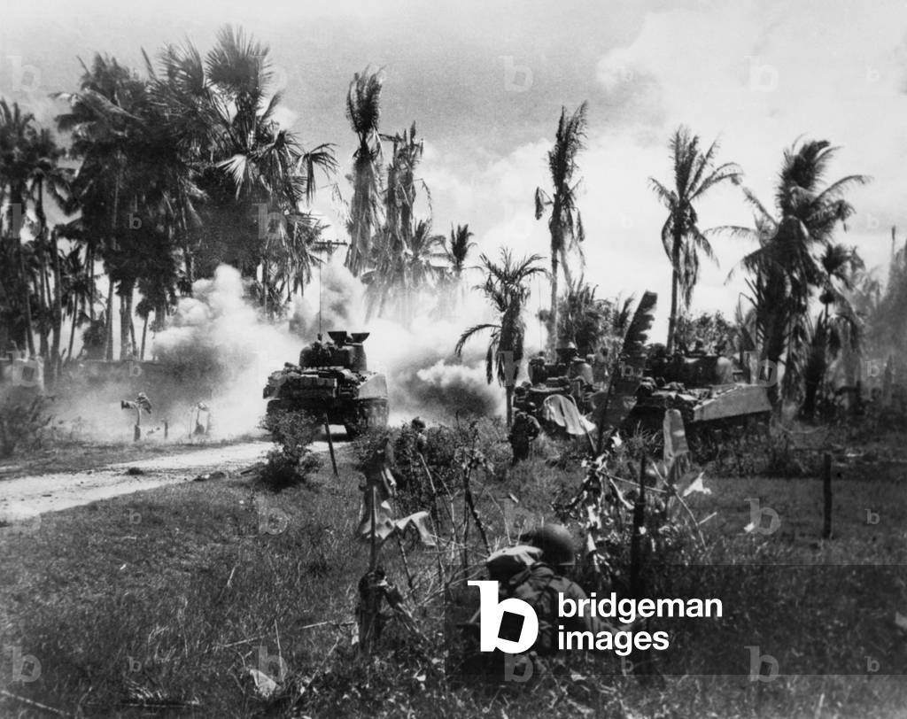 U.S. Troops take cover behind advancing tanks while moving up on Japanese positions. March 18, 1945. Pansy Island, Philippines, World War 2.