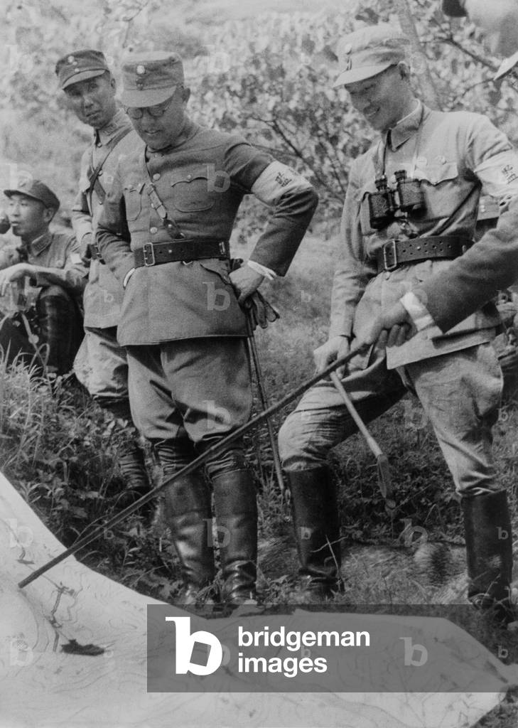 Generalissimo Chiang Kai-shek and other Chinese officers. They are outdoors with a map planning their next military campaign. c. 1937-1943. Photo by Marcus J. Clark