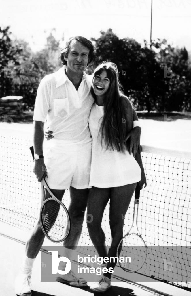 Hugh Hefner and Barbi Benton pose for a cover shot for 'Tennis Magazine'. ca 1972.