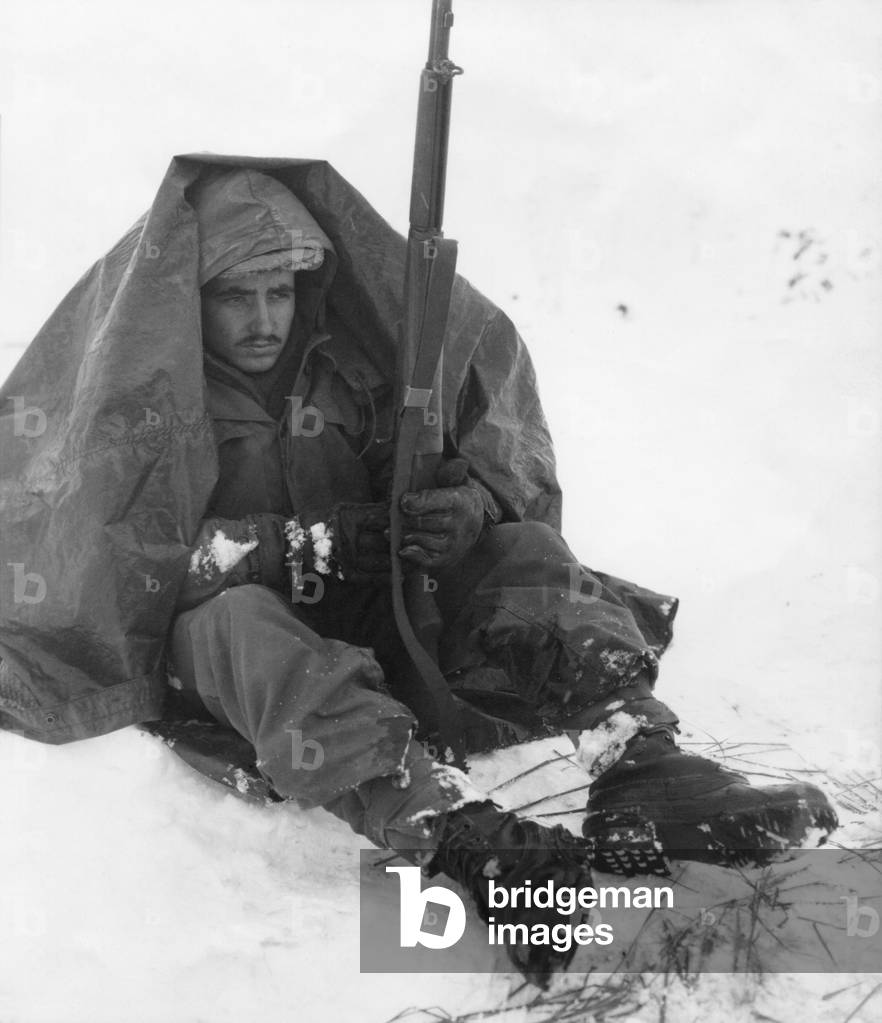 Soldier of the U.S. 19th Infantry Regiment uses his poncho to get protection from the biting wind and cold. Yoju area Jan. 10, 1951, after the withdrawal of U.N. forces from North Korea. Korean War, 1950-53