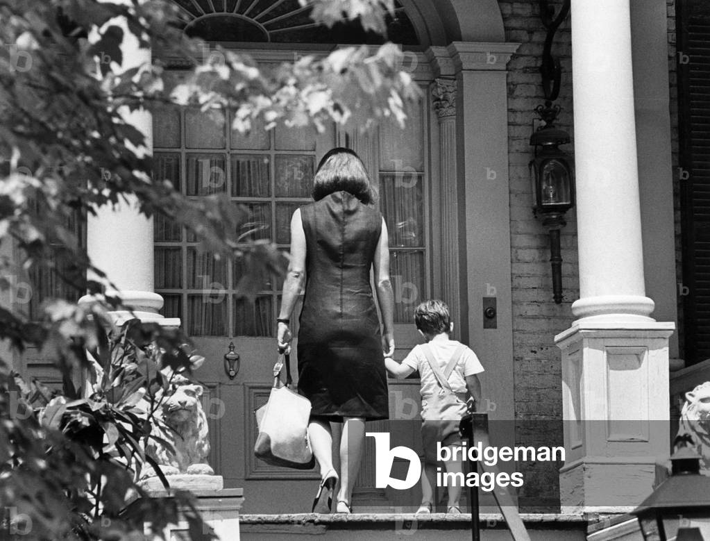 Jacqueline Kennedy and John F. Kennedy Jr., walking up the front steps of house