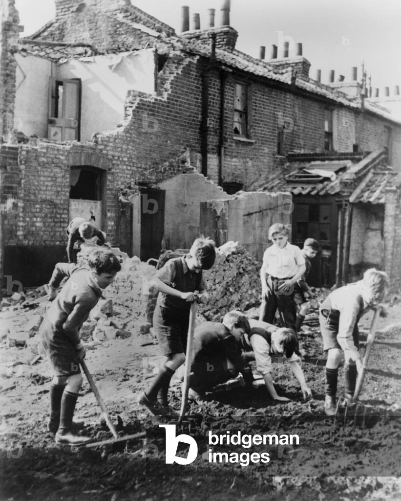 World War 2, Battle of Britain. Young boys with pitchforks and rakes start a garden next to buildings damaged by air raids. Between 1940-1945