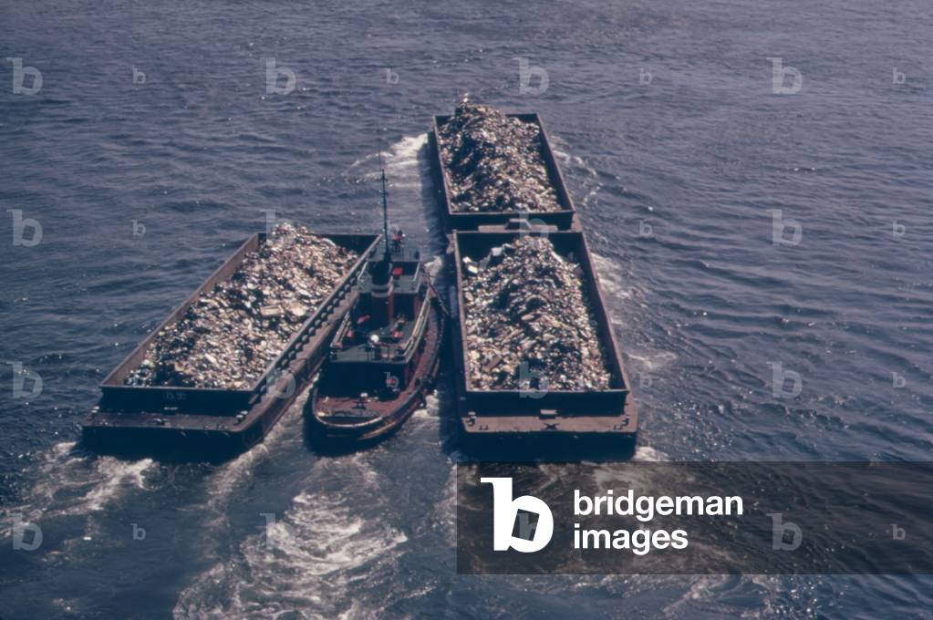 Tug boats tow barges of garbage down the East River to an overflowing Staten Island landfill. In the early 1970s New York City produced 26 000 tons of solid waste daily. c. 1973-75