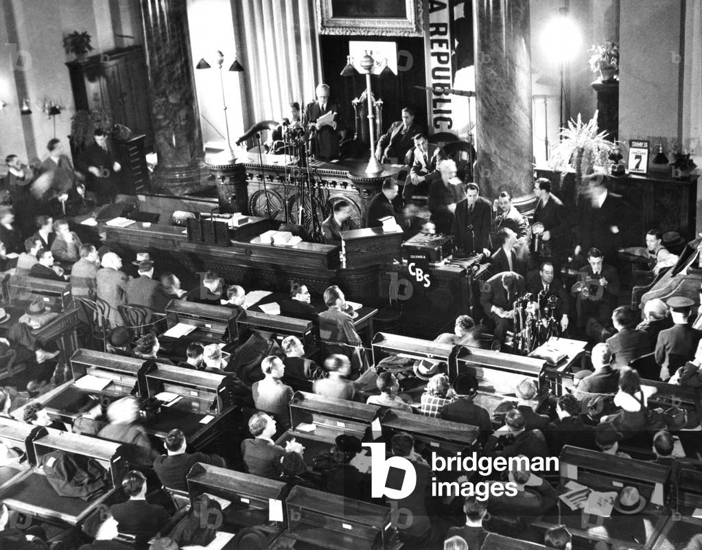 Governor Culbert Olson pardoned Tom Mooney, the Preparedness Day Bombing prisoner. Jan. 7, 1939. Scene in the State Capitol with as Governor Culbert Olson at the Podium, Thomas Mooney is at center right, sitting near microphones and a photographer
