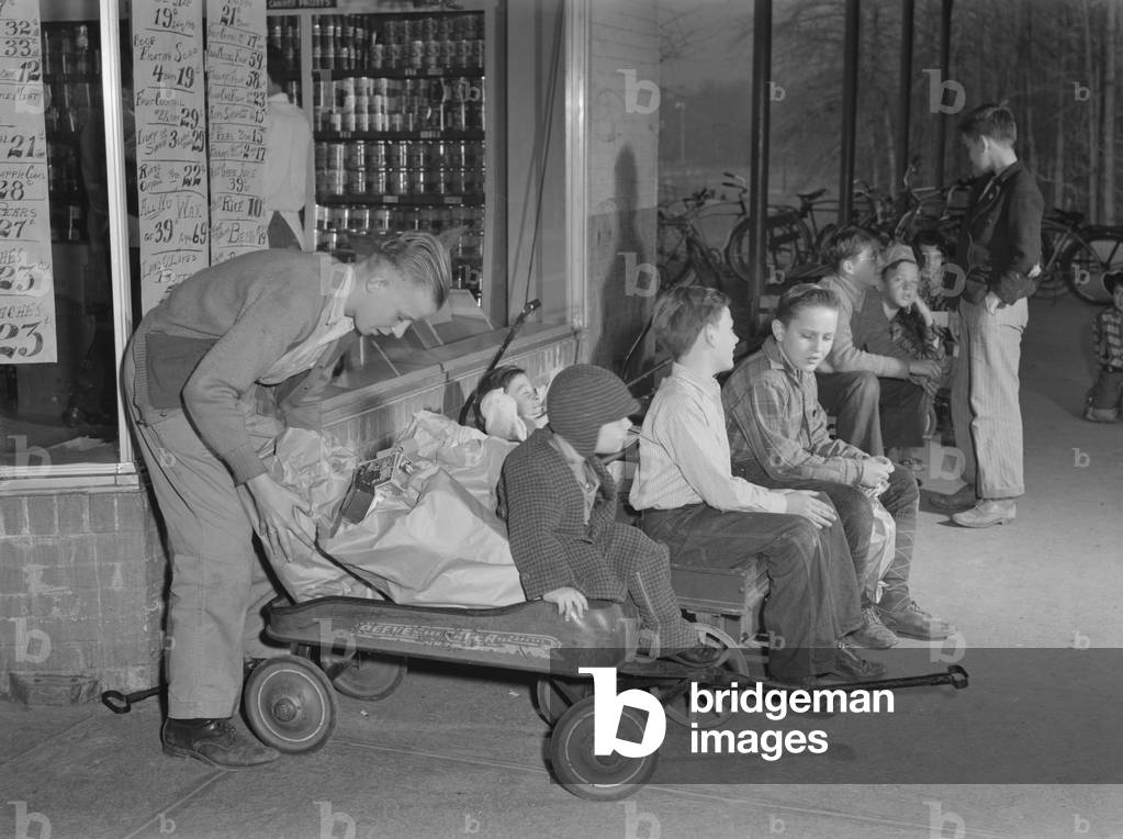 Youngsters hiring out their express wagons to haul groceries in suburban Greenbelt, Maryland. World War 2 tire and gasoline rationing created this business opportunity. Nov. 1942