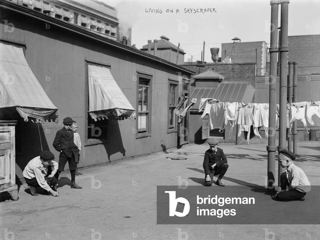 Boys playing games on the roof of a skyscraper, titled: 'Living on a skyscraper' c.1920s