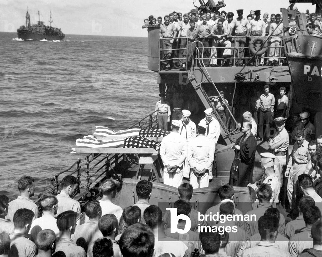 Burial at sea for 2 of the 644 sailors killed in the sinking of USS Liscome Bay, Nov. 24, 1943. The aircraft carrier was torpedoed by a Japanese submarine in the Gilbert Islands. In the foreground are some of the 272 survivors of the Liscome Bay