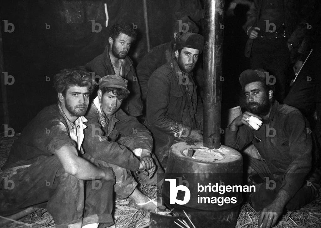Released American and Australian POWs warming up by a stove. They are in the 24th Division medical clearing station after being returned to U.S. lines by Chinese Communists, February 10, 1951. Korean War, 1950-53