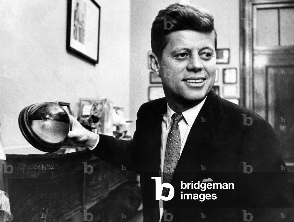 Senator John F. Kennedy, holds a mounted half of a cocoanut in his Senate office. After his boat was torpedoed during World War II, he and his men reached shore and carved a message on the cocoanut; a native carried it to a U.S. military installation. February 26, 1959