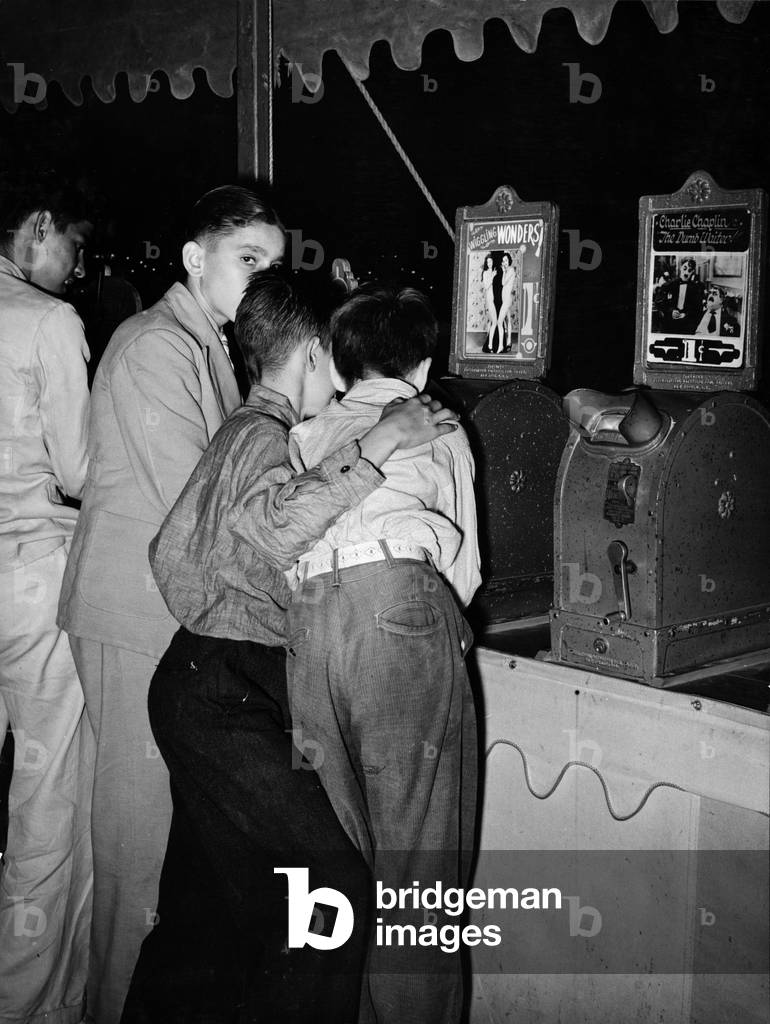 Boys looking at penny movies at South Louisiana State Fair, viewing WIGGLING WONDERS, next to a machine showing Charlie Chaplin in THE DUMB WAITER, photograph by Lee Russell, October, 1938