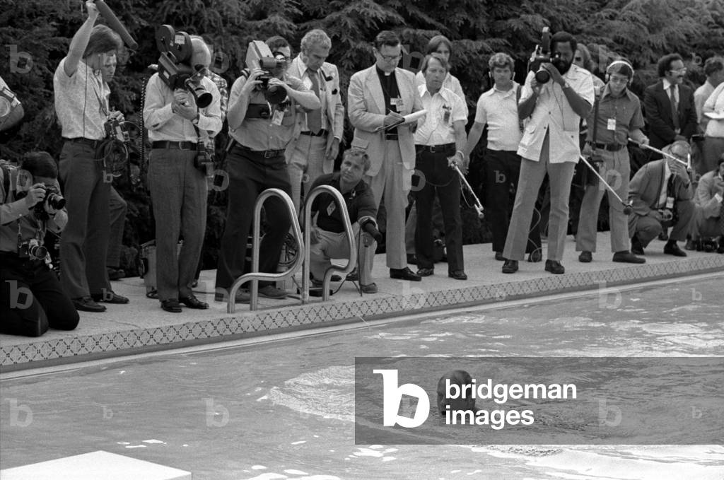 The White House press cover the non-event of President Gerald Ford taking his first swim in the new White House pool. President Nixon replaced the previous indoor pool with a bowling alley. July 5 1975