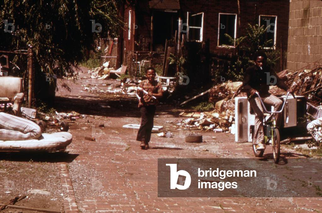 1970s Americ. Two young boys pass through a trash-strewn alley of Chicago, c. early 1973s