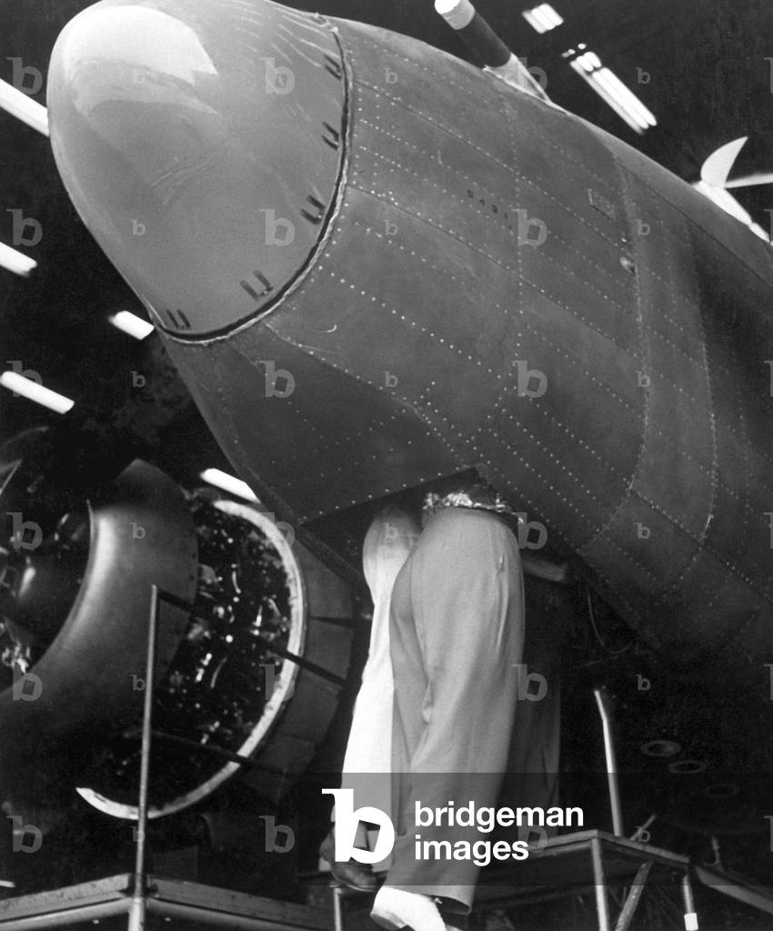 Two women workers standing through the bombardier's hatch at the Vega aircraft plant. Burbank, California, during World War 2, August 1943