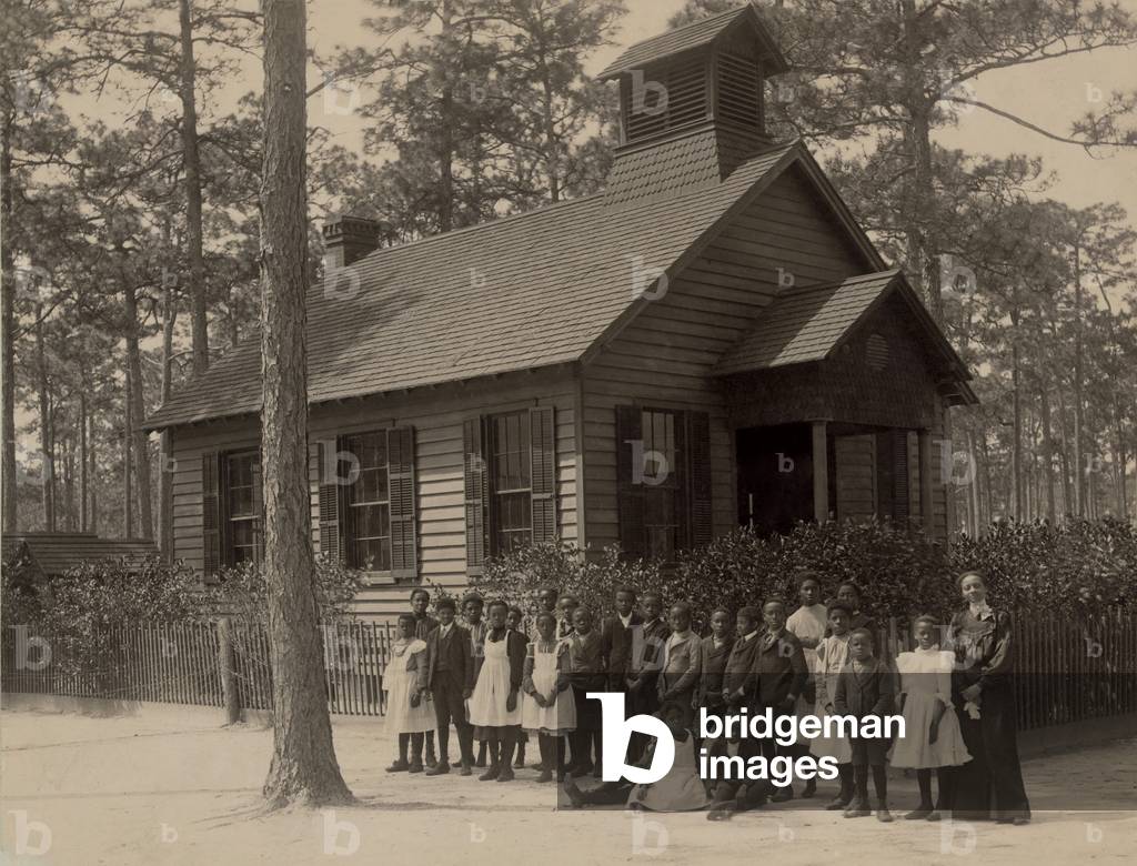 African American school children posed with their teacher outside a segregated one-room school, in South Carolina. c. 1905