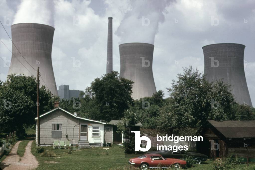 Water cooling towers of the John Amos Power Plant loom over a West Virginia home across the Kanawha River. The coal powered plant was named after a state politician
