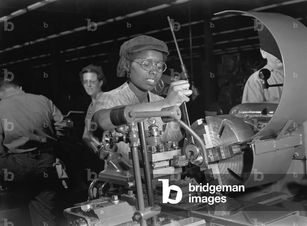 African American woman lathe operator at a Midwest supercharger plant. In the background are white workers in the racially integrated workforce during World War 2. c. 1942-45