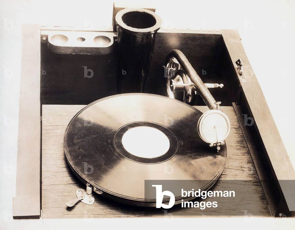 gramophone: Top view of gramophone, in square wooden cabinet, with curved arm, needle and record, circa 1914.