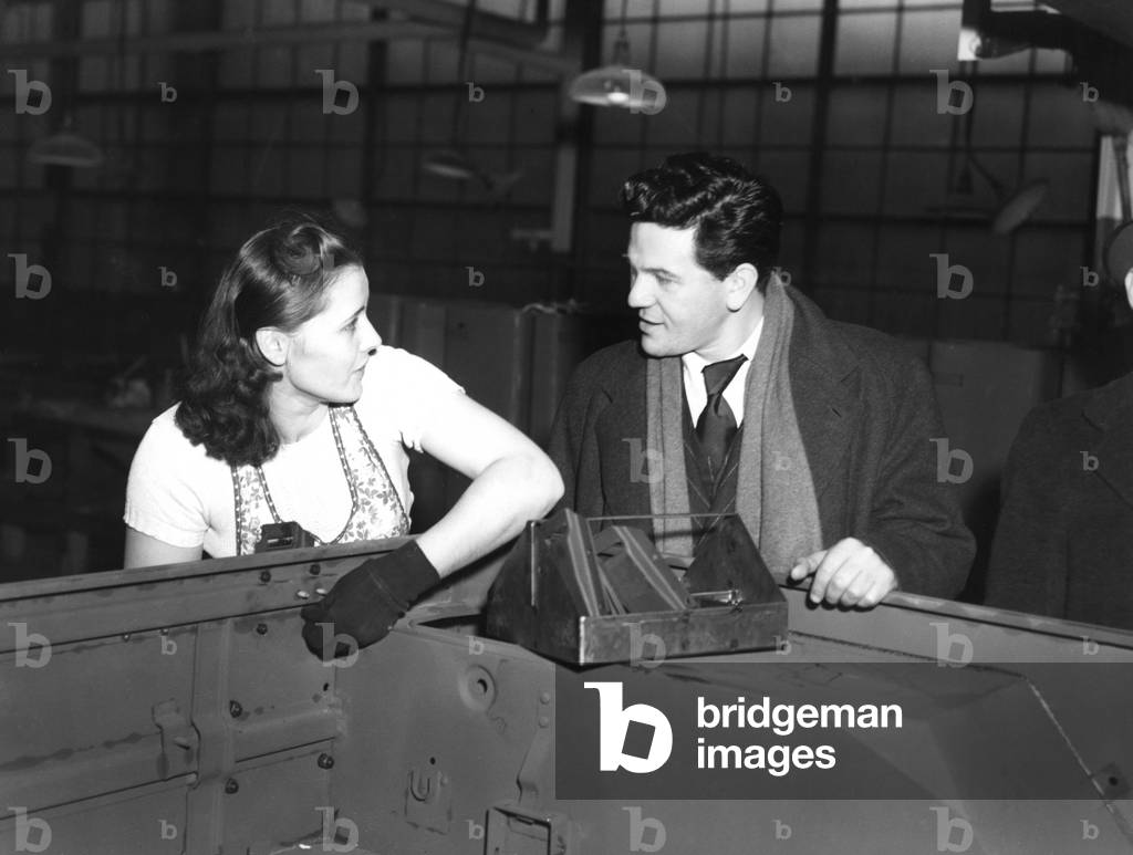 Toledo war defense worker MARGARET MENDOZA, turning out jeeps for Uncle Sam, is visited by actor JOHN GARFIELD during his bond drive tour, 1943