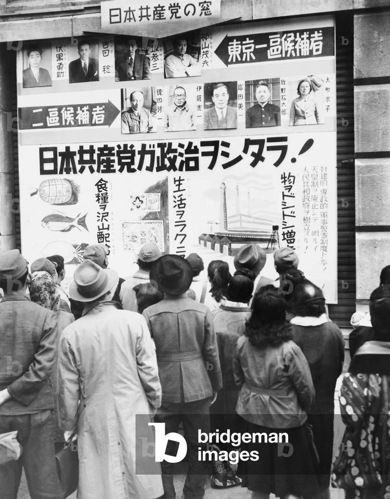 Japanese people read a Communist party election poster outside the Mitsukoshi department store. Tokyo, Japan. April 16, 1946.