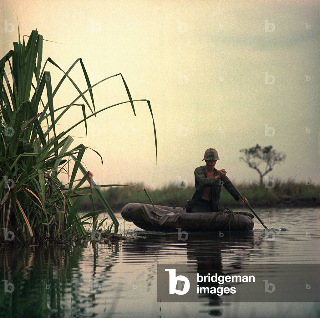 Vietnam War, Private First Class David Sletten, medic, Company B, 1st Battalion, 27th Infantry, 25th Infantry Division, paddles a three-man assault boat down the canal toward a breaking point during Operation Tong Thang I, c.late 1960s
