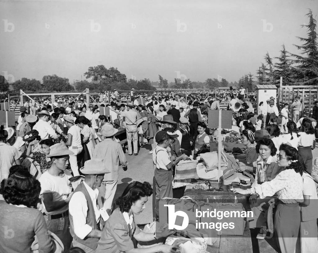 Japanese-Americans at the Santa Anita Assembly Center where family groups identify their baggage prior to departure to the relocation camps that would be their homes for the duration of World War II. 1942