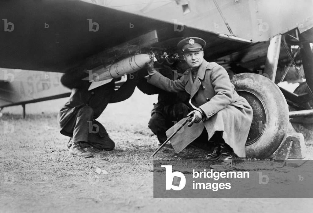 Brigadier General Billy Mitchell and another man, attaching a bomb under wing of airplane. c. 1925. He advocated military aviation and foresaw the vulnerability of ships to aerial bombing. His fervor resulted in a court-martial for insubordination and his resignation