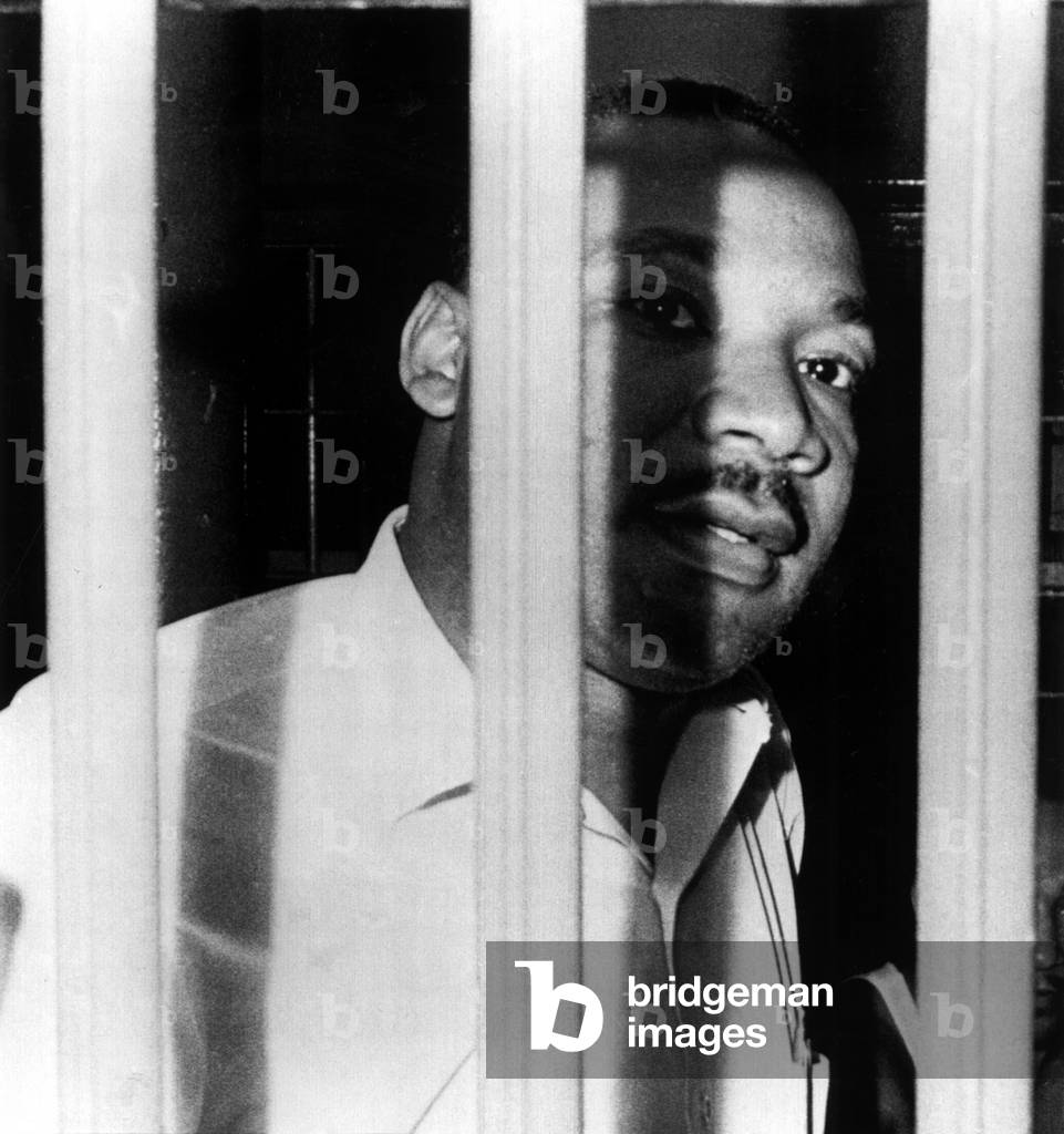 MARTIN LUTHER KING, JR, peers between the bars of his jail cell, Florida, 1962 (photo)