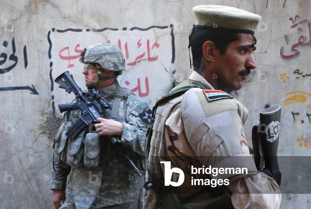 US and Iraqi army soldiers stand guard a market in the Al Doura district of Baghdad Iraq providing security for US Ambassador Ryan Crocker who was touring the city. April 5 2007